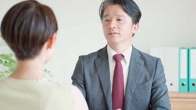女性に真剣な表情で話をするスーツを着た日本人男性