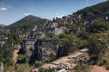 Fototapeta premium Ancient Greek abandoned city of Kayakoy in Fethiye, Turkey. A city on a mountain. Destroyed, empty houses. Top view, drone shot. View of the abandoned city and the mountains behind in the background