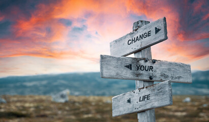 change your life text quote caption on wooden signpost outdoors in nature with dramatic sunset...
