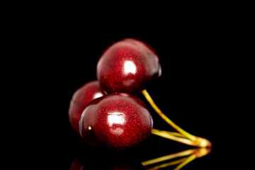 Three sweet cherries, close-up, isolated on a black background.