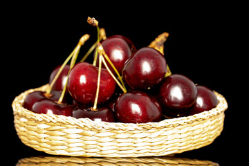 Several sweet cherries in a glass bowl, close-up, isolated on a black  background.