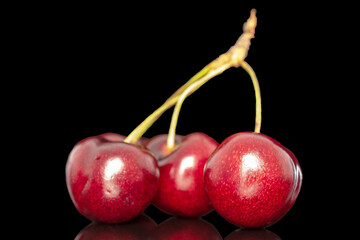 Three sweet cherries, close-up, isolated on a black background.