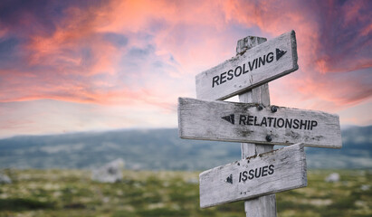 resolving relationship issues text quote caption on wooden signpost outdoors in nature with dramatic sunset skies. Panorama crop.