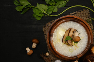 Rice porridge with soft boiled egg, shiitake mushroom and spring onion in wooden bowl on a served table