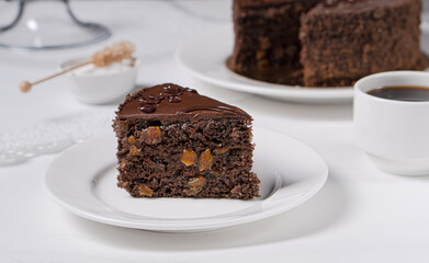 A piece of chocolate cake with apricot jam and chocolate cream on a light table.