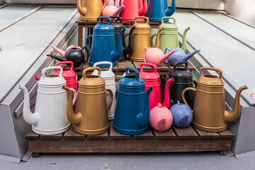 Different sizes of different colors of watering cans for sale in a flower shop