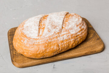 Freshly baked bread on cutting board against white wooden background. perspective view bread with copy space