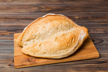 Freshly baked bread on cutting board against white wooden background. perspective view bread with copy space