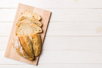 Freshly baked bread slices on cutting board against white wooden background. top view Sliced bread
