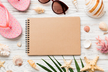 Blank writing book with summer beach accessories on background, copy space. Flat lay with copy space