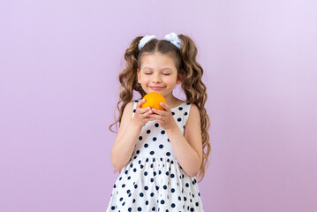 A child sniffs an orange on an isolated background. Vitamin for baby food.