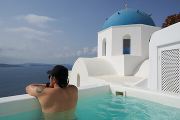 A man is swimming in front of the blue-domed church.