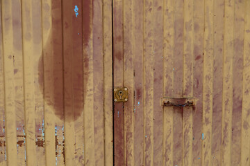 A weatherd brown yellow metal door