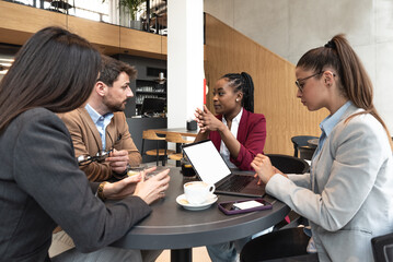 Group of young business freelancers people sitting in cafeteria on staff meeting discussing about future of their company. Colleagues having conversation about hiring new employee. Selective focus