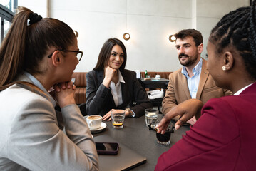 Group of young business freelancers people sitting in cafeteria on staff meeting discussing about future of their company. Colleagues having conversation about hiring new employee. Selective focus   