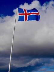 Icelandic flag against cloudy sky.
