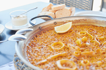 Arroz a banda served in a paella pan ready to be eaten directly with spoons in an outdoor...