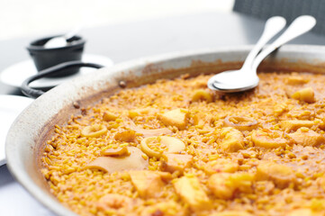 Arroz del senyoret served in a paella pan ready to be eaten directly with spoons in an outdoor...