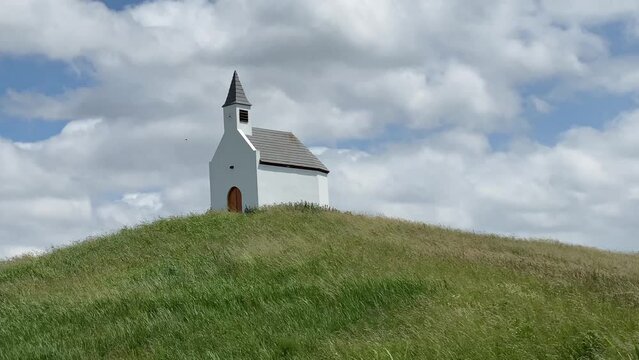 Small rustic white chapel church on the hill.