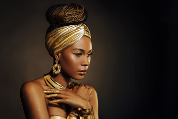 Portrait Closeup Beauty Fantasy afrikanische Frau, Gesicht in Goldfarbe. Golden glänzende schwarze Haut. Model Mädchen gemischte Rasse. Glamouröser arabischer Turban, Schmuckzubehör. Professionelles Metallic-Make-up © kharchenkoirina