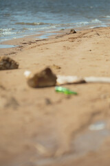 Fototapeta na wymiar Bear glass bottle on the sand. Garbage on the dirty beach. Selective focus