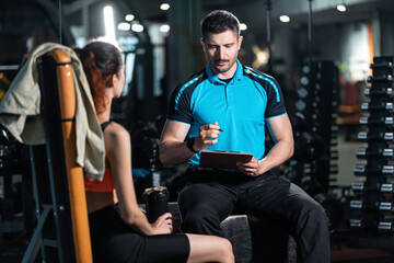 young personal trainer man talking with woman athlete and plan workout in gym