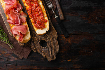 Spanish cured serrano ham with olive oil and toasted bread, on old dark  wooden table background, top view flat lay, with copy space for text - obrazy, fototapety, plakaty