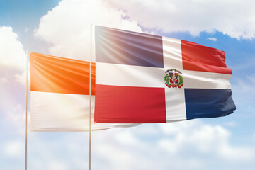 Sunny blue sky and flags of dominican republic and indonesia