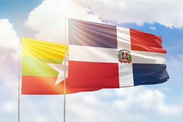 Sunny blue sky and flags of dominican republic and myanmar