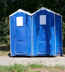 Two portable toilet cabins in park at dry sunny summer day