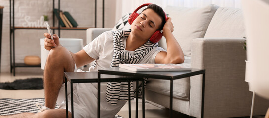 Sleepy young man listening to music at home
