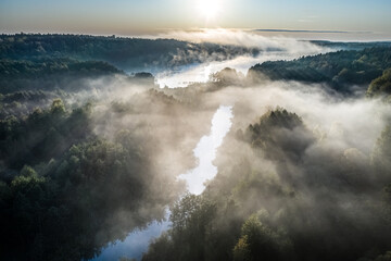 Mist over the river with sunrays at sunrise, aerial view
