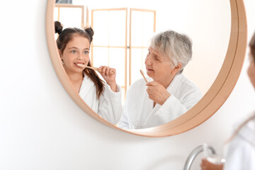 Little girl and her grandma brushing teeth in bathroom