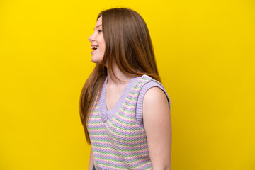 Young caucasian woman isolated on yellow background laughing in lateral position