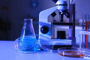 Test tube, conical flask and safety goggles on table in medical laboratory
