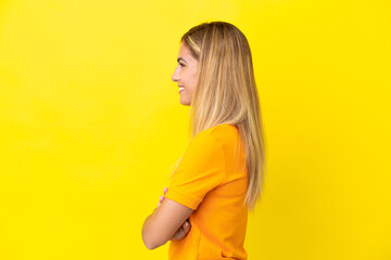 Blonde Uruguayan girl isolated on yellow background in lateral position