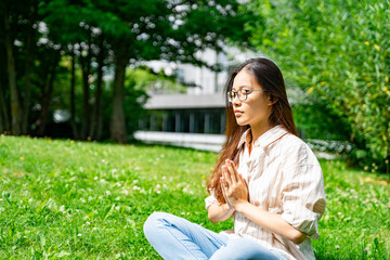 Young Asian Thai, Vietnamese or Chinese woman in casual clothes sitting in lotus yoga pose...
