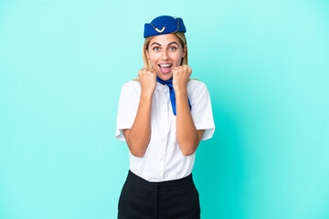 Airplane stewardess Uruguayan woman isolated on blue background celebrating a victory in winner position
