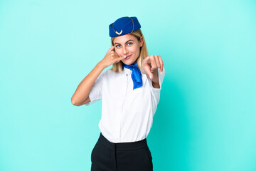 Airplane stewardess Uruguayan woman isolated on blue background making phone gesture and pointing front