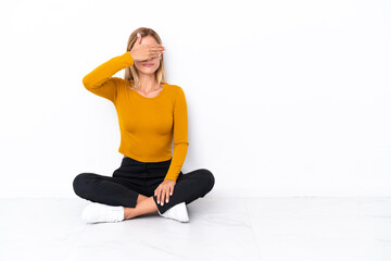 Blonde Uruguayan girl sitting on the floor covering eyes by hands. Do not want to see something