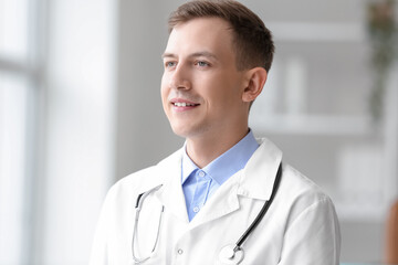 Male medical assistant with stethoscope smiling in clinic