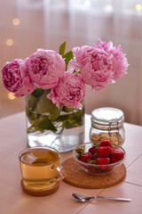 Fototapeta na wymiar Beautiful pink peonies, strawberries and breakfast.