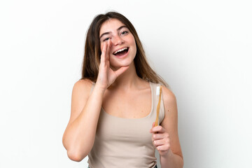 Young caucasian woman brushing teeth isolated on white background shouting with mouth wide open