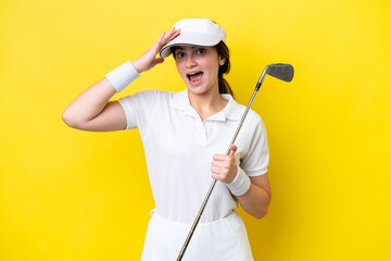 young caucasian woman playing golf isolated on yellow background with surprise expression