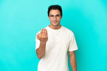 Caucasian handsome man over isolated blue background inviting to come with hand. Happy that you came