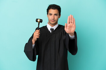 Judge over isolated blue background making stop gesture