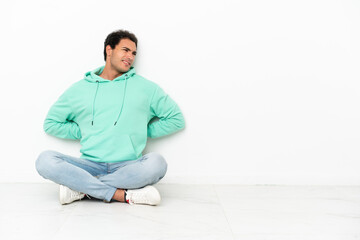 Caucasian handsome man sitting on the floor suffering from backache for having made an effort
