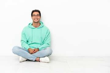 Caucasian handsome man sitting on the floor with glasses and happy