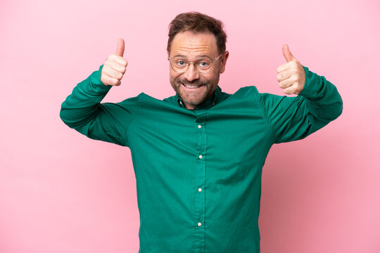 Middle age caucasian man isolated on pink background giving a thumbs up gesture