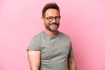 Middle age man wearing a band aids isolated on pink background smiling a lot